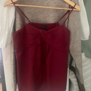 Vinröd linnetopp från Banana Republic - Säljer en vinröd linnetopp från Banana Republic med smala axelband och twistad detalj framtill. Toppen har en smockad rygg för extra komfort och sitter snyggt på kroppen. Perfekt att styla till jeans eller kjol!       