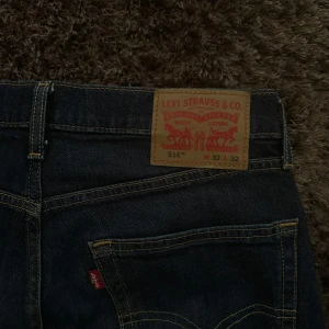 Levi's 514 jeans mörkblå - Säljer ett par klassiska Levi's 514 jeans i mörkblå denim. Byxorna har raka ben, fem fickor och tydliga kontrastsömmar. Passar perfekt till dig som gillar en tidlös jeansstil. Midjemått W32 och längd 32.