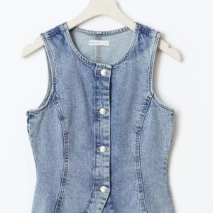 Jeansväst med knappar - Snygg jeansväst i ljusblå denim med markerad midja och silverfärgade knappar framtill. Andvänder 2 gånger och väldigt snygg! 