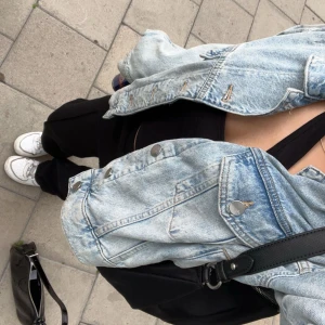 Jeansjacka  - Säljer en ljusblå jeansjacka med klassiska bröstfickor och silverfärgade knappar. Jackan har en avslappnad passform och är perfekt att slänga över en t-shirt eller hoodie. Enkel och tidlös design som passar till det mesta.