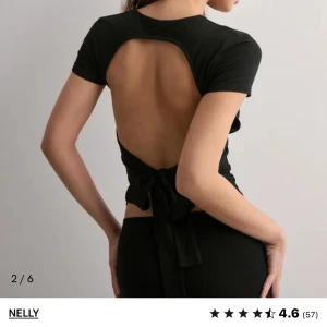 Svart croppad topp med öppen rygg från Nelly - Trendig svart topp från Nelly med korta ärmar och croppad passform. Toppen har en snygg öppen rygg med knytning baktill som ger en unik look. HELT NY LAPPEN KVAR. Storlek xxs men mer än xs