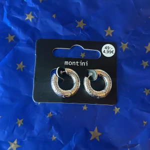Silverfärgade örhängen - Säljer ett par snygga, runda örhängen från Montini/ur&penn i silverfärg. De har en glittrig yta som ger extra lyster och är perfekta för att lyfta din stil. Kommer på originalkortet. Fick dom i en mistery bag från ur&penn. Säljer då jag är guld människa och dom är inte riktigt min stil. (ALDRIG ANVÄNDA)