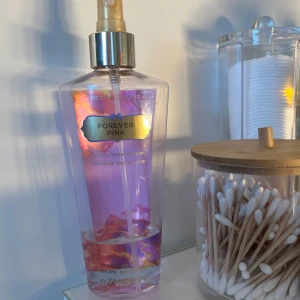 Forever Pink body mist från Victoria's Secret - En söt och blommig body mist från Victoria's Secret i doften Forever Pink. Flaskan är genomskinlig med rosa och guldiga detaljer samt en praktisk sprayfunktion. Innehåller 250 ml och har en feminin design med blommotiv. Det är den orginala flaskan och även en doft som inte säljs längre så den är väldigt svår att få tag på!