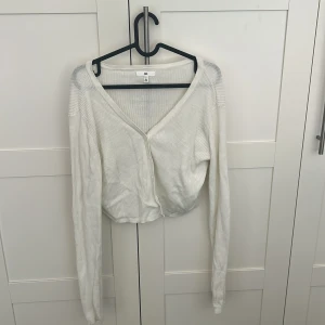 Vit croppad kofta från BP. - Säljer en vit croppad kofta från BP. som var använd en gång. Koftan är väldigt bekväm och har ett skönt och mjukt material och den är i storlek L.