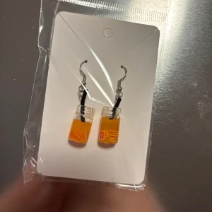 Örhängen med orange vätska i glasflaska - Unika örhängen formade som små glasflaskor fyllda med orange vätska och ett svart sugrör. Perfekta för att ge en lekfull touch till din stil. (Billigt material) 