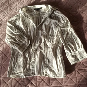 En cool randig skjorta från KappAh l🤩 - Säljer en stilren randig skjorta från KappAhl i storlek 40. Skjortan har trekvartsärmar och knappar framtill. Med den här skjortan blir en väldigt cool outfit🌸😎