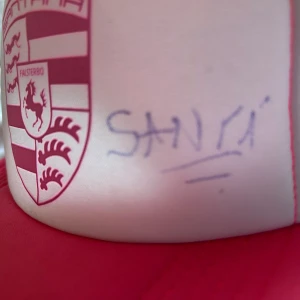 Keps signerad av papi santana - Snygg rosa och vit keps med nätpaneler och en broderad Falsterbo-logga framtill. Perfekt för en solig dag eller som en stilren accessoar. Justerbar passform för optimal komfort.