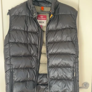 Svart dunväst från Parajumpers - Svart parajumpers väst med 2 små hål (ett på baksidan strax under axeln och en som är på nedre delen av ryggen) som är täckta med svart tejp och syns knappt storleken är y-l men sitter som S