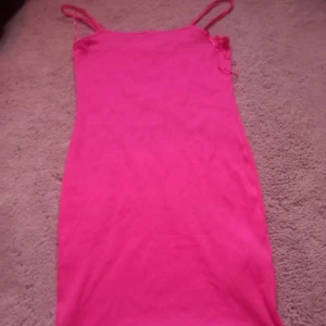 Rosa ärmlös klänning - Säljer en snygg rosa klänning med smala axelband. Klänningen är ärmlös och har en figurnära passform som framhäver silhuetten. Perfekt för sommarens varma dagar eller en utekväll.