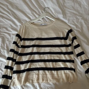 Randig tröja från Zara - Säljer en stilren randig tröja från Zara i beige och svart. Tröjan har långa ärmar och en rund halsringning. Perfekt för en avslappnad look.