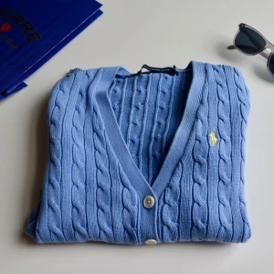  Ralph Lauren kofta -  blå kofta från Ralph Lauren med kabelstickat mönster och knappar framtill. Den har långa ärmar och två praktiska fickor. Original priset var 2 689 kr men säljer mycket billigare. 