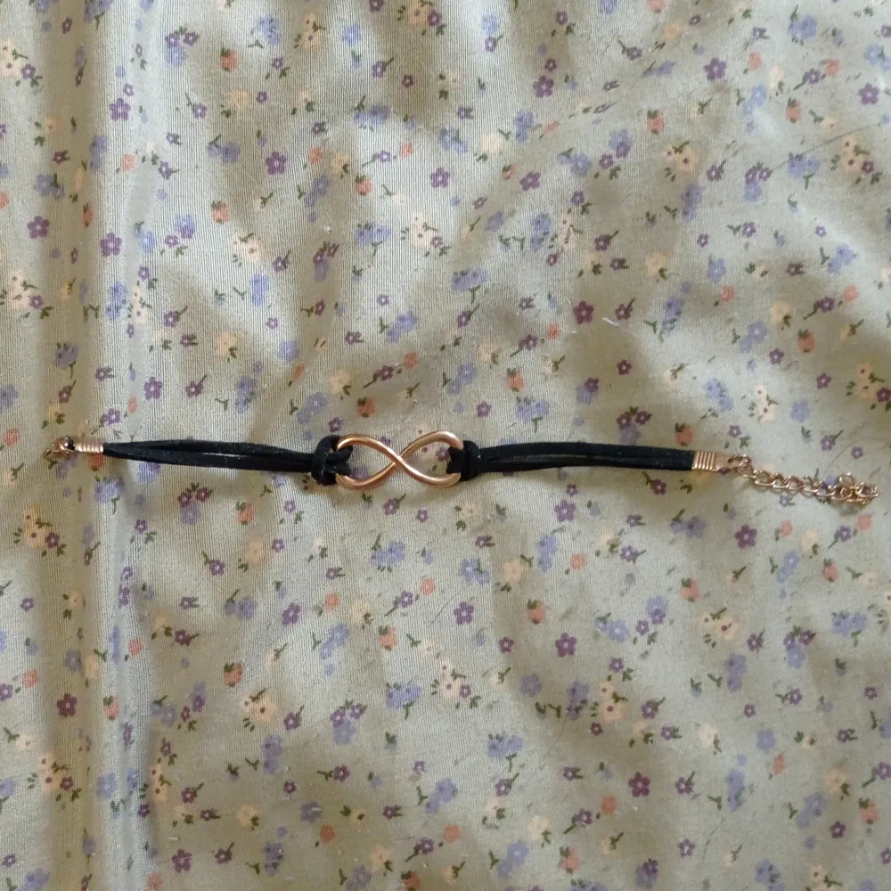 Snyggt svart armband med en guld oändlighetssymbol i mitten. Armbandet har en justerbar kedja för perfekt passform. Perfekt för att lägga till en subtil touch av stil till din outfit från shein.. Asusteet.