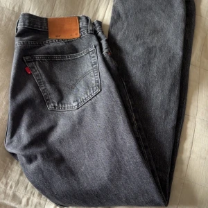 Grå Levis jeans - Säljer ett par klassiska grå Levis jeans med en straight passform. De har en midwaist design och är tillverkade i slitstarkt denim. Perfekta för en avslappnad stil.