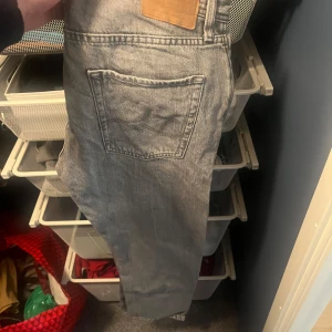 Grå jeansbyxor - Säljer ett par grå jeansbyxor med en avslappnad passform. Byxorna har en klassisk design med fem fickor och knappgylf. Perfekta för en casual look.