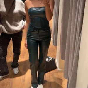 skinnbyxor och tubtopp - Snygga gröna skinnbyxor med hög midja och raka ben. Byxorna har en stilren design med fickor bak. Matchande grön tubtopp i skinnmaterial för en komplett look.