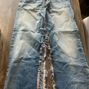 Blå kjol från Weekday - Snygg kjol från Weekday med slitna detaljer längs benen. De har en klassisk femficksdesign och en bekväm passform. Perfekta för en cool stil