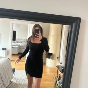 Svart långärmad klänning - Snygg svart långärmad klänning med en tight passform och en liten slits. Perfekt för en stilren look.