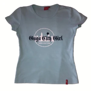 Ljusblå t-shirt från Guga Couture - Snygg ljusblå t-shirt från Guga Couture med trycket 'Guga City Girl' på framsidan. Den har en rund halsringning och korta ärmar. Färgen är mest lik bild 3,4 och 5. Och storleken är mer xs änn m.