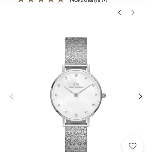 Silverfärgad klocka från Daniel Wellington - Elegant klocka från Daniel Wellington med en glittrig silverfärgad mesharmband och en stilren urtavla. Urtavlan har diskreta markeringar och en minimalistisk design som passar perfekt för en sofistikerad look.