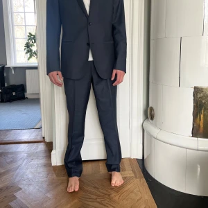 Svart kostym från Filippa K - Elegant blågrå kostym från Filippa K i storlek 50. Kostymen har en klassisk kavaj med två knappar och matchande byxor. Perfekt för formella tillfällen.