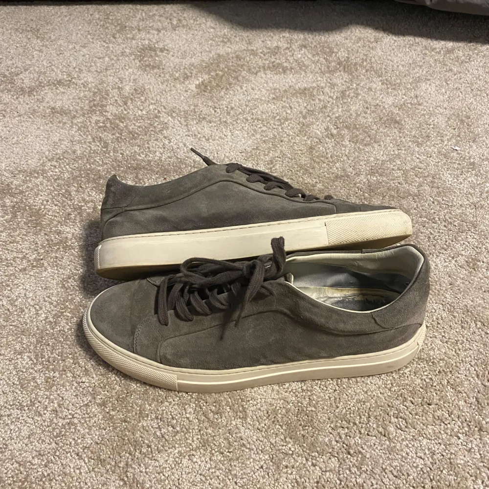 Snygga grå sneakers i mocka med snörning och vit sula. Perfekta för en stilren och avslappnad look. Passar bra till både jeans och chinos.. Kengät.