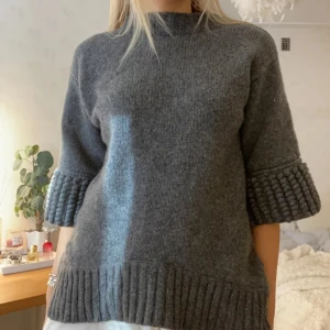 Grå stickad tröja från Selected Femme - Säljer en mysig grå stickad tröja från Selected Femme. Tröjan har trekvartsärmar med ribbade detaljer och en rund halsringning med dragkedja på axlarna. Perfekt för kyliga och gosiga dagar!🩷Lånade bilder och köpt på plick men bara använt en gång. 