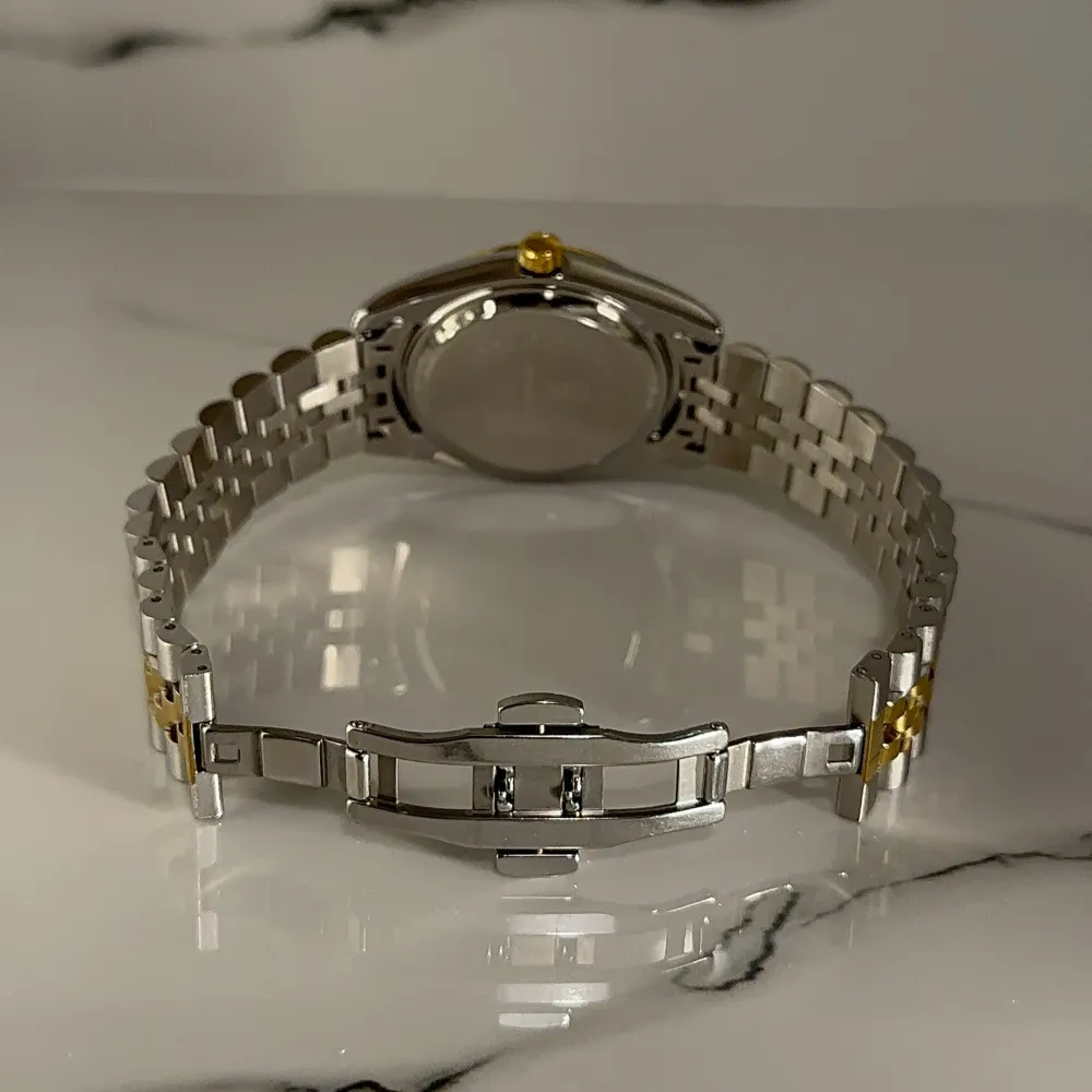 Snygg klocka med en grön urtavla och guldiga detaljer. Armbandet är i tvåtonat stål och guld, vilket ger en elegant look. Klockan har en datumvisning. Perfekt för den som vill ha en stilren accessoar. BOX, EXTRA LÄNK och LÄNKJUSTERARE medföljer! PRISET KAN DISKUTERAS VID SNABB AFFÄR!. Asusteet.