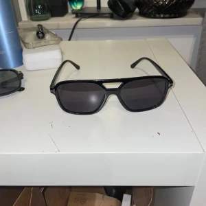 Svarta solglasögon  - Snygga svarta solglasögon med en modern design. Perfekta för en stilren look. Bågarna är robusta och ger en cool touch till din outfit. 