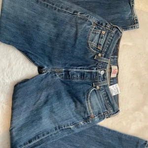 Levis 501 jeans - Klassiska Levis 501 jeans i blå denim. Dessa jeans har en rak passform och är högmidjade med knappgylf. Perfekta för en avslappnad stil.