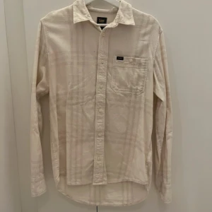 Beige långärmad skjorta från Lee - Jättefin beige och vit rutig Lee skjorta. Är i man storlek men kan användas av både tjejer och killar.🤍