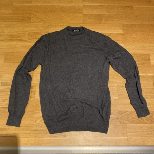 Grå kashmirtröja från Jaxie - Säljer en stilren grå tröja från Jaxie i mjuk kashmirblandning. Perfekt för kyliga dagar med sin klassiska design och långa ärmar. Passar både till vardags och mer uppklädda tillfällen.