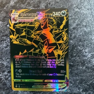 Eternatus VMAX Pokémonkort - Säljer ett Eternatus VMAX Pokémonkort med en häftig holografisk design. Kortet har 340 HP och en speciell förmåga kallad 'Eternal Zone'. Perfekt för samlare eller spelare som vill förstärka sin kortlek med en kraftfull VMAX Pokémon. Väldigt Sällsynt pris kan diskuteras.