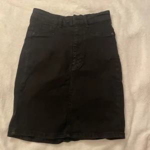 Svart jeanskjol från Perfect Jeans - Snygg svart jeanskjol från Perfect Jeans i modellen Molly. Kjolen har en klassisk femficksdesign och en bekväm passform. Perfekt för en stilren look.