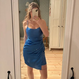 Blå satinklänning  - Wow vilken klänning! Sitter som en smäck och är dessutom väldigt bekväm. Man behöver inte ha bh under även om man har större byst som jag. Använd en gång och därför i bra skick! Dragkedjan där bak har en liten bristning men man kan fortfarande dra upp den utan problem. 