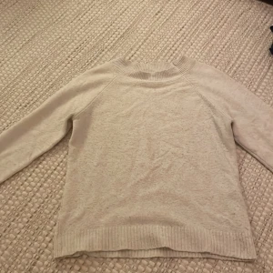 Beige stickad tröja från Vero Moda - Säljer en mysig beige stickad tröja från Vero Moda. Tröjan har långa ärmar och en ribbad krage samt ribbade muddar vid ärmslut och nederkant. Perfekt för kyliga dagar!