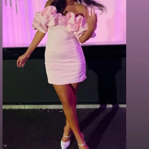 Rosa offshoulder klänning - Säljer en söt rosa offshoulder klänning med volangdetaljer. Klänningen är kort och har en figurnära passform, perfekt för en festlig kväll. Klänningen är en M men har sytt in den hos en skräddare så skulle säga att den är som en S/Xs🩷den är använd endast en kväll och är som ny!