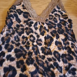 Leopardmönstrad linne med spetsdetaljer - Säljer ett snyggt leopardmönstrat linne med v-ringning och spetsdetaljer i halsen. Perfekt för en trendig look.