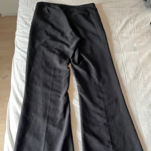Svarta kostymbyxor - Snygga svarta kostymbyxor med vida ben från Gina Tricot . Byxorna har en klassisk design med dragkedja och knapp framtill. Perfekta för en stilren look.
