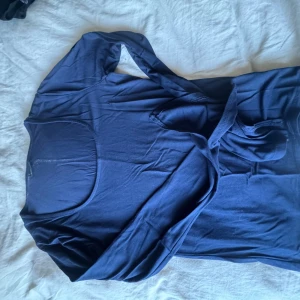 Marinblå soft ware topp från Gina Tricot - Snygg marinblå topp från Gina Tricot med långärmad design och uringad . Perfekt för en stilren look. Den har öppning nere vid ärmarnas slut 