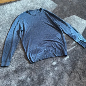 Blå stickad tröja - Säljer en stilren blå tröja med rund halsringning. Tröjan har långa ärmar och är perfekt för en avslappnad look. Passar bra till både jeans och chinos. Storlek är M, men passar också bra till S