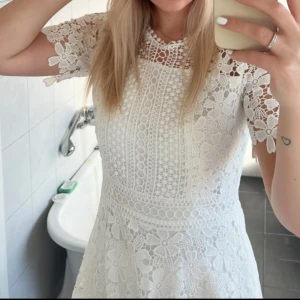 Vit studentklänning - Säljer en elegant vit spetsklänning som passar perfekt till studenten. Den har ett blommigt spets mönster. Använd 1 gång och ser ut som ny. Storlek 34. Nypris 999kr
