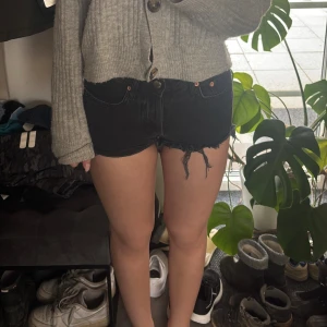 Svarta jeansshorts med medelhög midja  - Snygga svarta jeansshorts med fransiga kanter. Perfekta för en avslappnad stil. De har en klassisk femficksdesign och knappgylf. De är medelhög media från mango. Hör av er vid frågor!!🩷