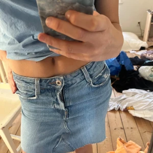 Jeanskjol från Zara - Säljer en snygg jeanskjol i ljusblå denim. Jag har sytt om ett par jeans till denna jeanskjol. Kjolen har en kort längd med slitna detaljer och en klassisk femficksdesign. Perfekt till sommaren