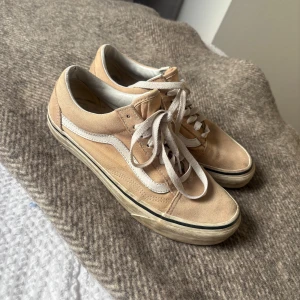 Beige sneakers från Vans - Säljer ett par klassiska beige sneakers från Vans off the wall med vit sula och snörning.  De är tillverkade i mocka och har en bekväm passform. Är väl använda därav pris 