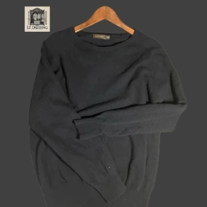 Svart tröja från Oscar Jacobson - Säljer en stilren tröja från Oscar Jacobson. Tröjan är långärmad och har en klassisk design med rund hals. Perfekt för en elegant och avslappnad look. Tröjan är i nyskick, aldrig använd!!! Nypris 1400kr. Kommer i original box :)