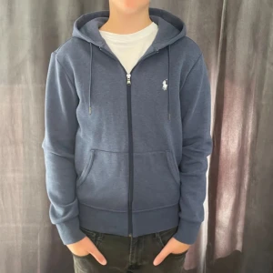 Blå hoodie från Ralph Lauren - Säljer nu en stilren zip hoodie med riktigt schyst färg från polo Ralph lauren! 💯 skick 8/10 den enda lilla skavanken är att det finns lite rivningar i materialet längst nere på armen på båda sidorna. Storlek XS (passar 165-170 skulle jag säga❗️) vid fler frågor och intresse kom privat 🤩🔥