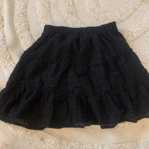 Svart kjol - Säljer en söt svart kjol med volangdetaljer. Kjolen har ett broderat mönster och elastisk midja för en bekväm passform. Perfekt för att ge en romantisk touch till din outfit. 🖤