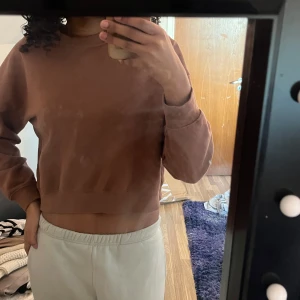 Brun/röd croppad sweatshirt - Säljer en brun croppad sweatshirt med långa ärmar. Perfekt för en avslappnad stil. Passar bra till både jeans och mjukisbyxor.