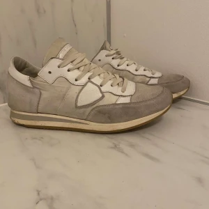 Grå och vita sneakers - Snygga sneakers i en kombination av grått och vitt. Skorna har en klassisk design med snörning och en bekväm sula. Perfekta för en stilren och avslappnad look.