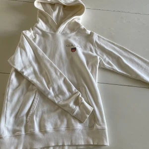 Vit hoodie från GANT - Säljer en stilren vit hoodie från GANT med broderat märke på bröstet. Det finns inte en enda defekt på den även fast den är vit så är skicket på den är nästan sprillans nytt. Står storlek 170 cm men om man är någon centimeter längre så borde det inte spela någon roll. Fritt fram att ställa frågor och be om någon mer bild och om priset är dåligt gör ett förslag men INGA SKAMBUD! Mvh Viggo